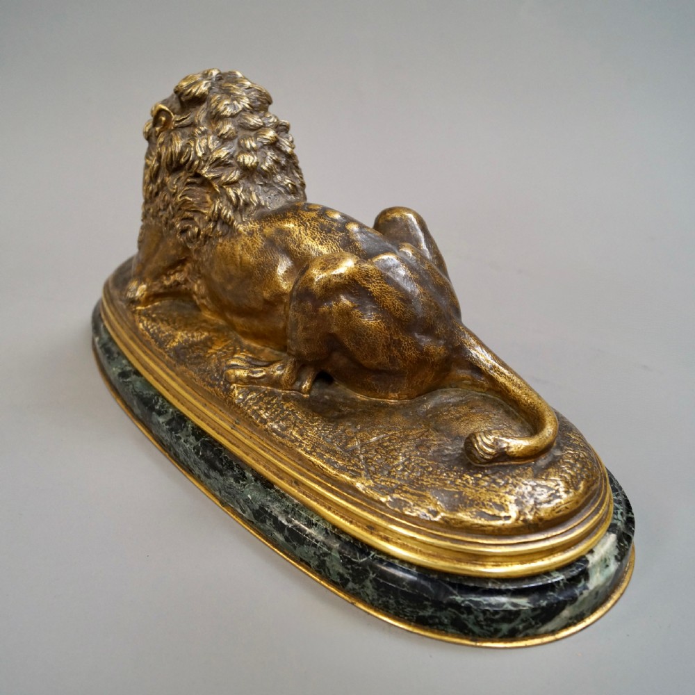 A nineteenth-century French gilded bronze sculpture of a recumbent lion with prey, set upon a moulded green marble plinth. View VII