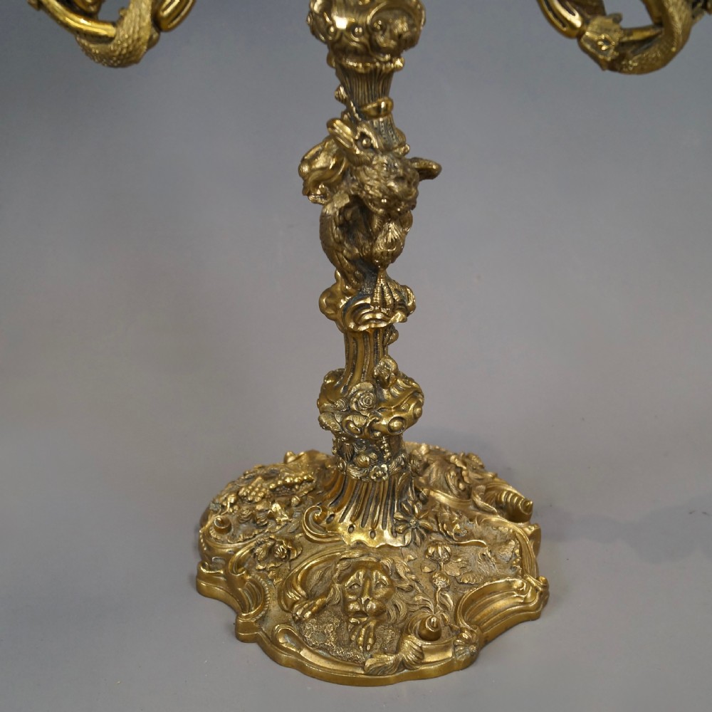 A pair of ornate French Rococo style ormolu three-light candelabra with scrolling leafy arms and intricate cast bases. View II