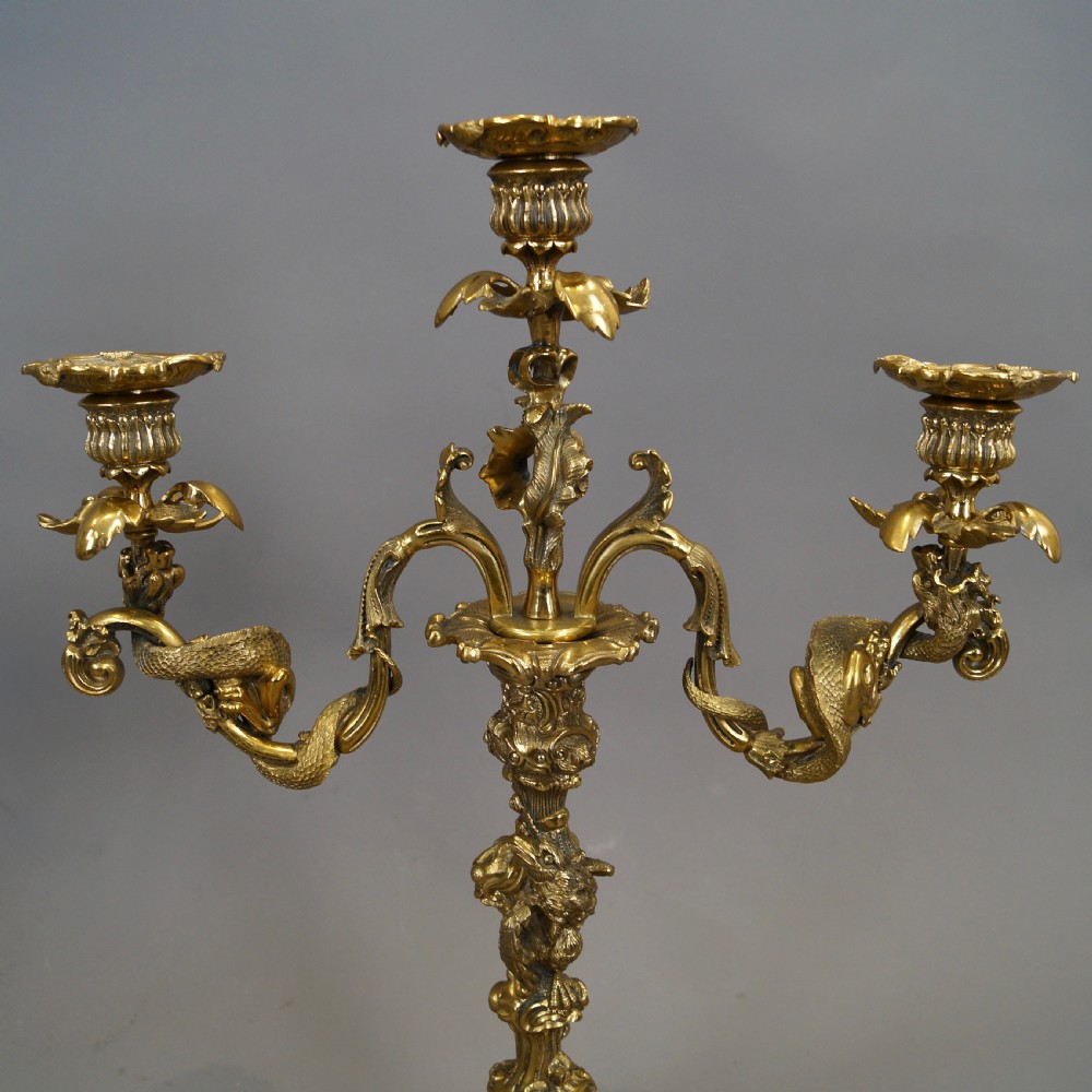 A pair of ornate French Rococo style ormolu three-light candelabra with scrolling leafy arms and intricate cast bases. View III
