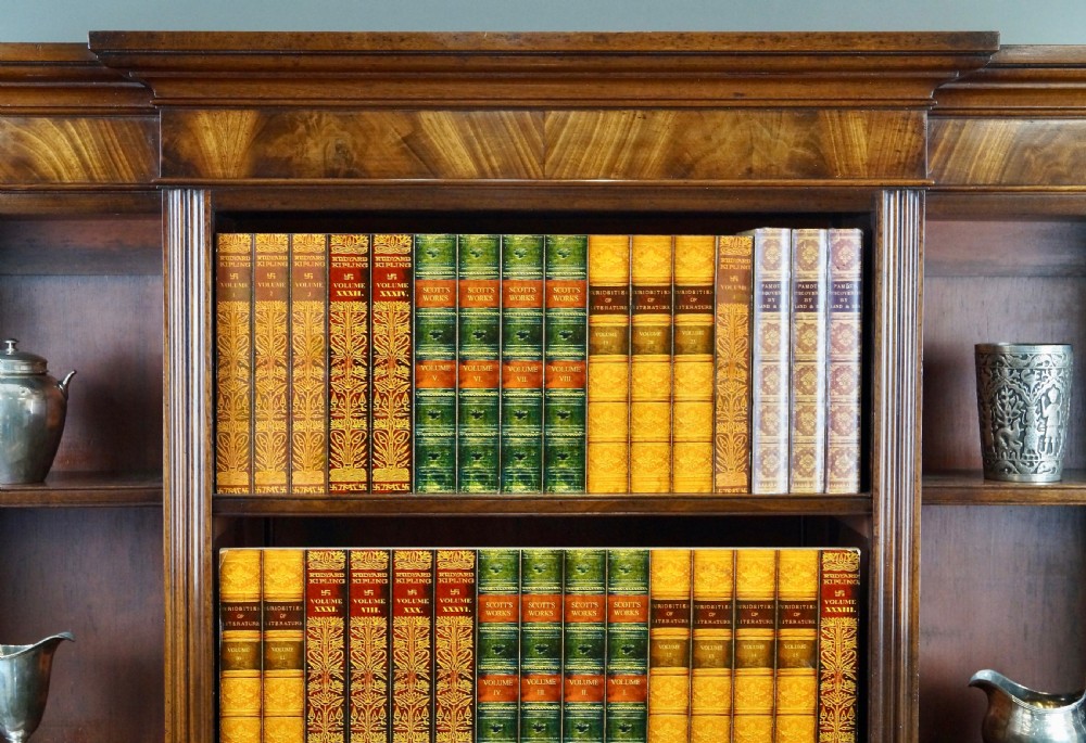 A mahogany breakfront bookcase featuring open upper shelving, flame mahogany panelled lower cupboard doors, and turned feet. View V