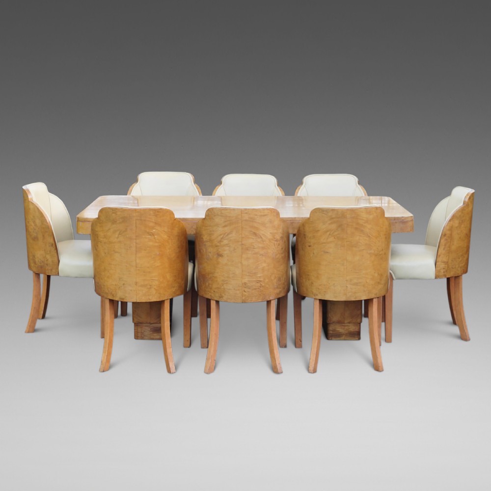An Art Deco burr walnut dining suite featuring a rectangular pedestal table with curved corners and matching cloud-back chairs upholstered in cream leather. View II