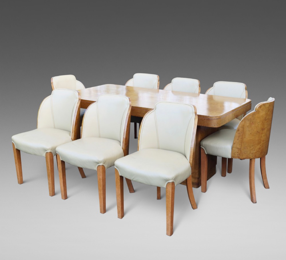 An Art Deco burr walnut dining suite featuring a rectangular pedestal table with curved corners and matching cloud-back chairs upholstered in cream leather. View III
