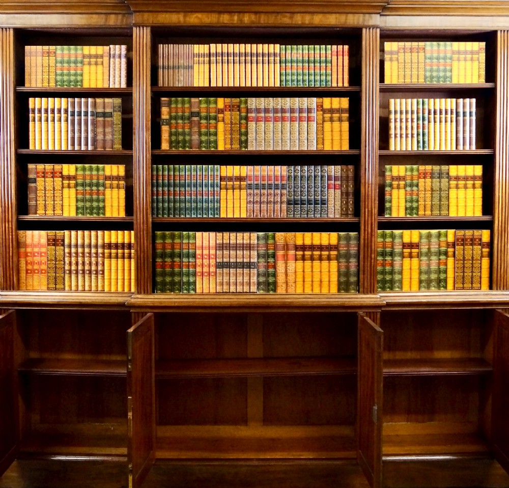 A late George III mahogany breakfront open bookcase featuring fluted pilasters, adjustable upper shelving, and panelled cupboard doors below. View IV