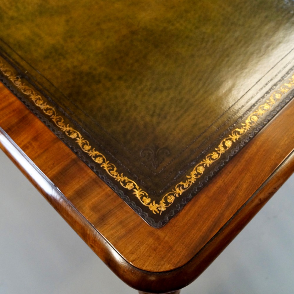 An antique mahogany partners writing table featuring a green leather inset top, two frieze drawers with turned handles, and turned legs on brass castors. View V