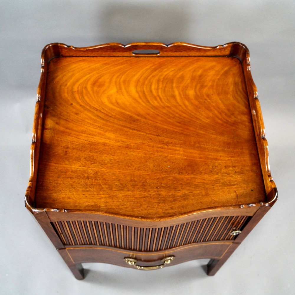 A Georgian mahogany tray-top commode featuring a galleried rim with cut-out handles, a slatted tambour door, and a lower serpentine drawer with brass pulls. View IV