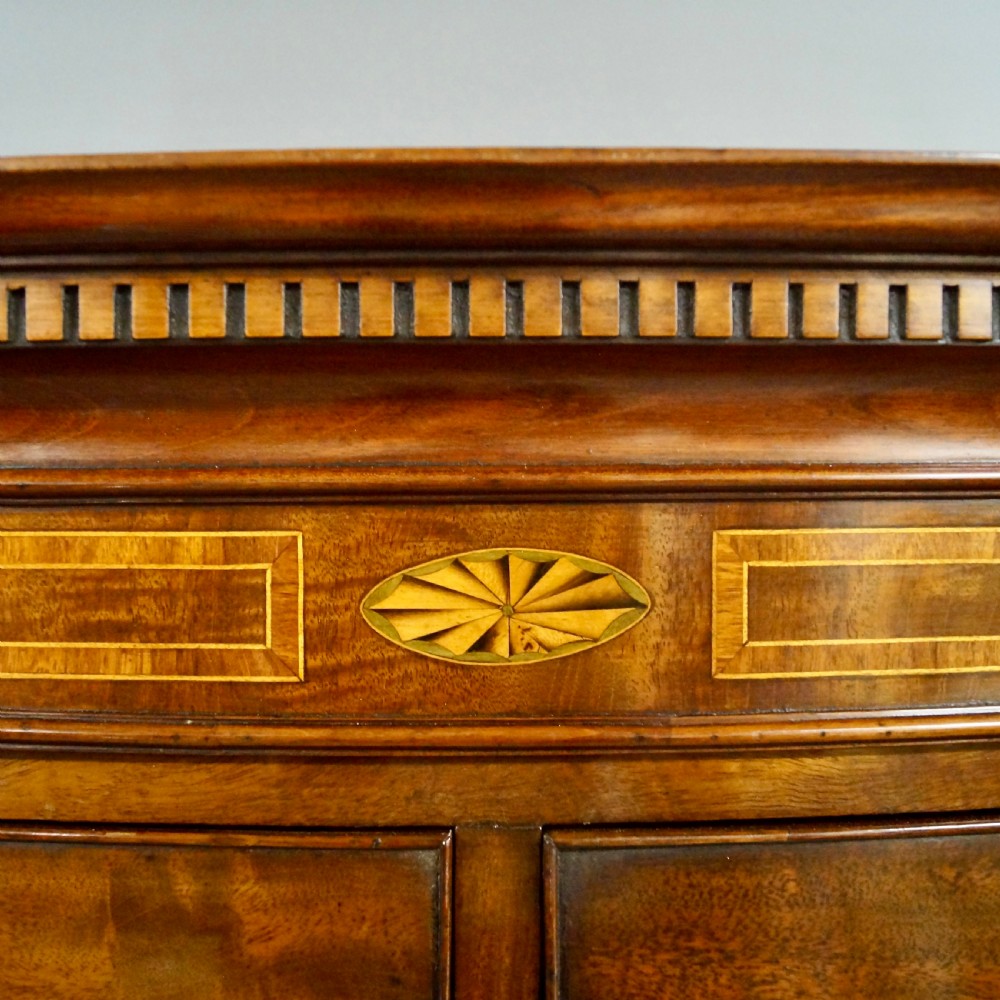 A Georgian mahogany bow-fronted tallboy featuring two sections with multiple graduated drawers, brass oval handles, an inlaid top frieze, and splayed bracket feet. View II