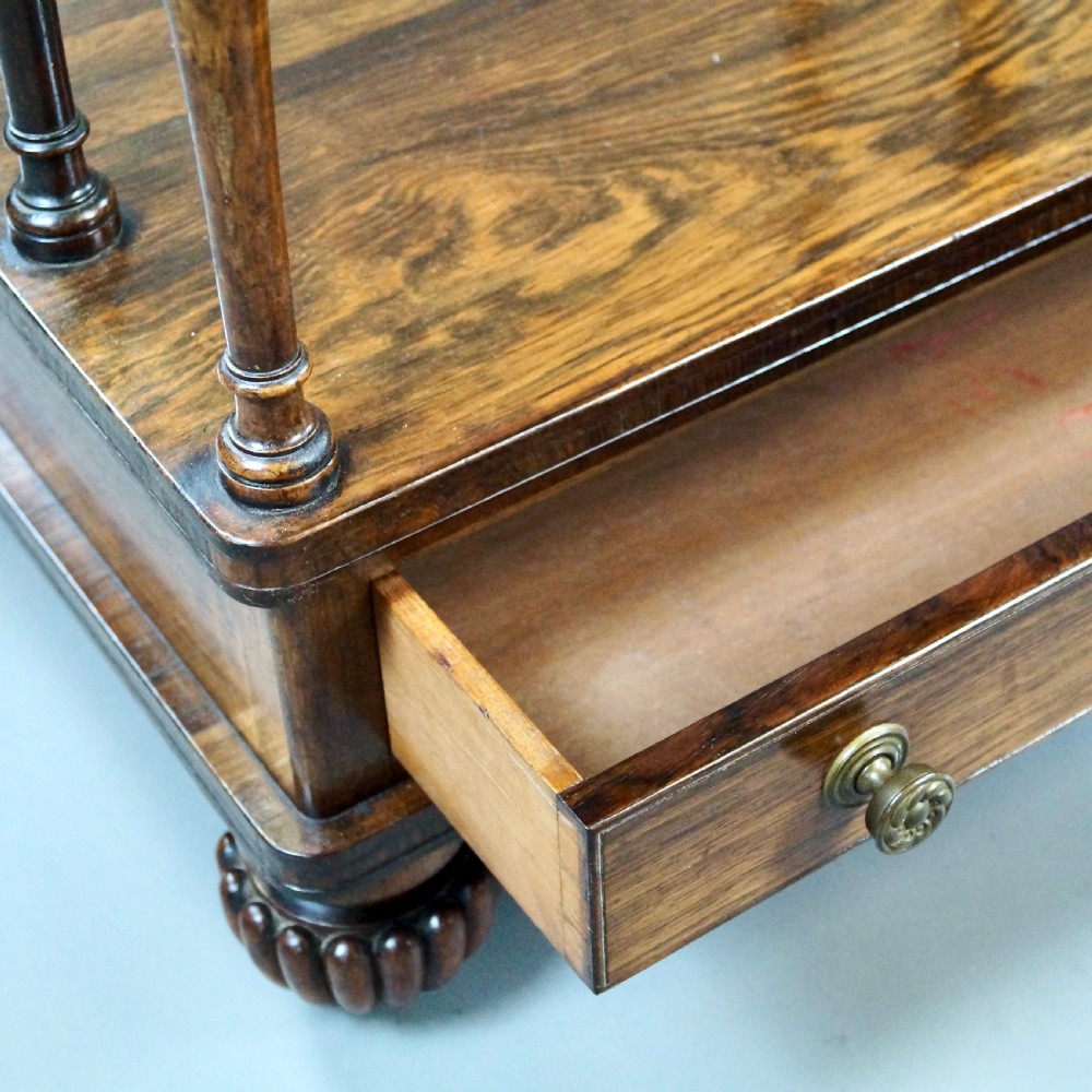 A pair of antique rosewood tiered whatnots featuring adjustable sloped reading tops, turned spindle supports, single drawers at the base, and lobed bun feet. View VI