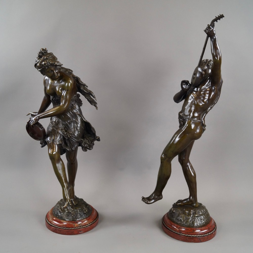 A pair of 19th-century dark bronze sculptures depicting a female musician with a tambourine and a male figure playing a lute, both set on circular red marble bases. View II