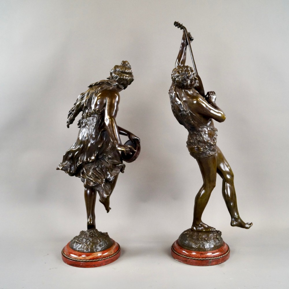 A pair of 19th-century dark bronze sculptures depicting a female musician with a tambourine and a male figure playing a lute, both set on circular red marble bases. View III