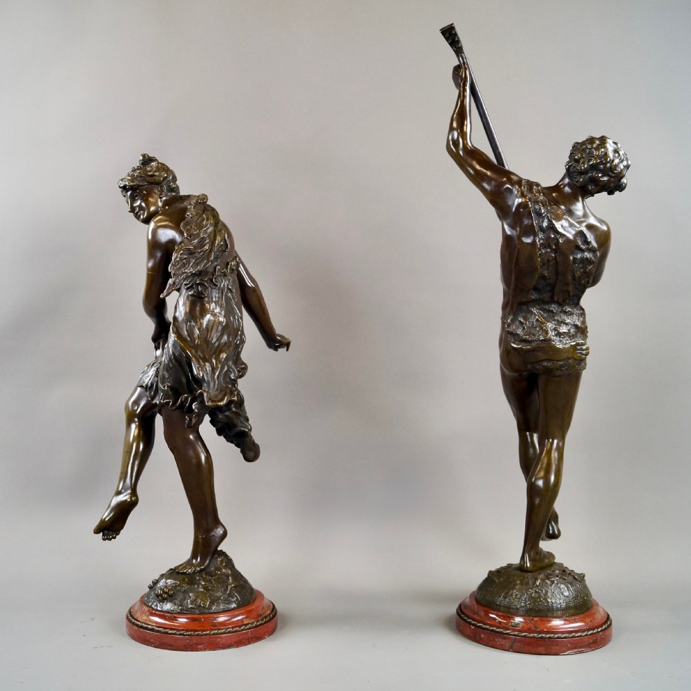 A pair of 19th-century dark bronze sculptures depicting a female musician with a tambourine and a male figure playing a lute, both set on circular red marble bases. View VI