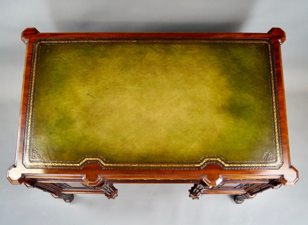 A Chippendale style dark mahogany Gothic Revival kneehole desk featuring carved tracery cupboard doors, a green leather writing surface, and carved legs. View III