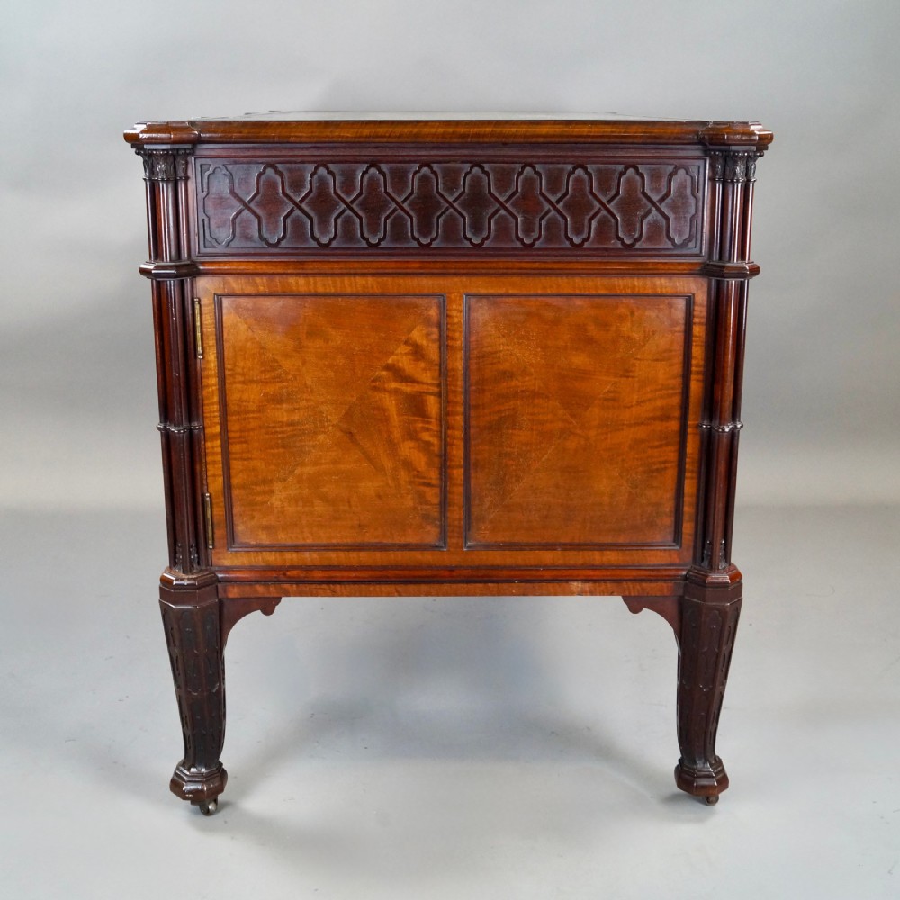 A Chippendale style dark mahogany Gothic Revival kneehole desk featuring carved tracery cupboard doors, a green leather writing surface, and carved legs. View V