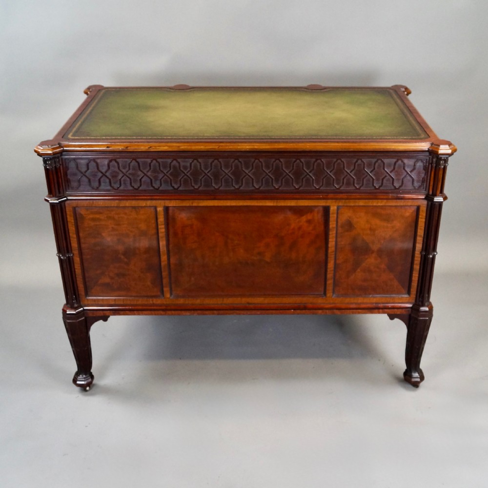 A Chippendale style dark mahogany Gothic Revival kneehole desk featuring carved tracery cupboard doors, a green leather writing surface, and carved legs. View VII