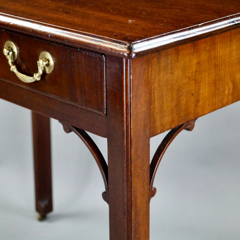 A George III mahogany side table featuring a rectangular top, single frieze drawer with brass swan-neck handles, corner brackets, and square legs on brass castors. View III