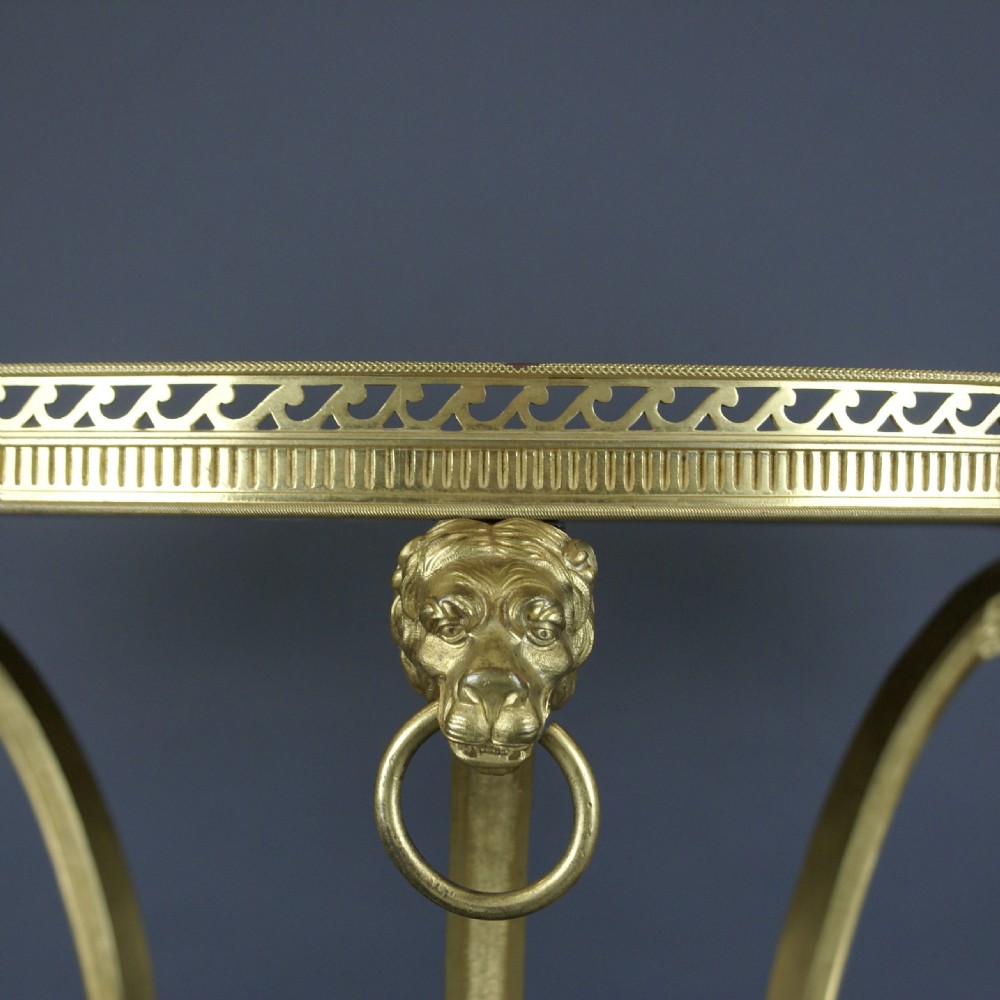 A circular French ormolu gueridon table featuring grey marble tops, a pierced gilt gallery, lion mask mounts with ring handles, and tripod legs terminating in paw feet. View II