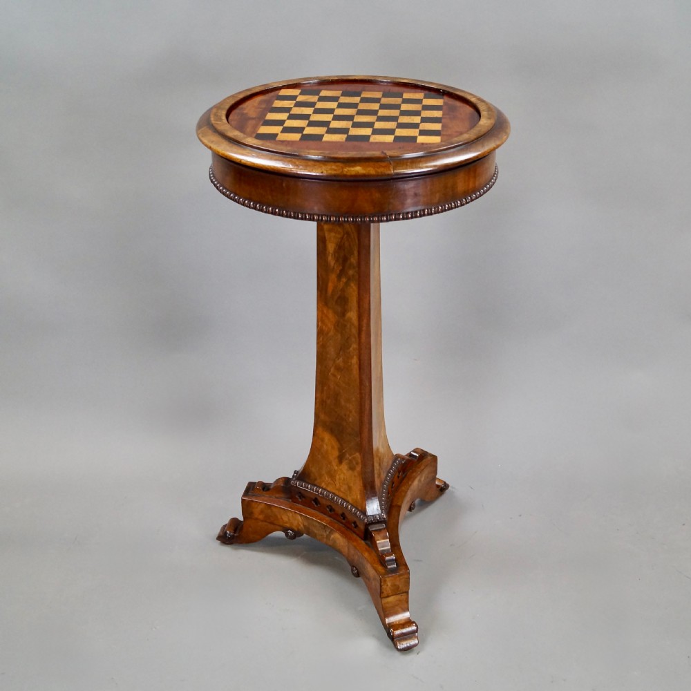 A William IV mahogany circular chess table with an inlaid board, tapered central stem, and triform base on scroll feet. View II