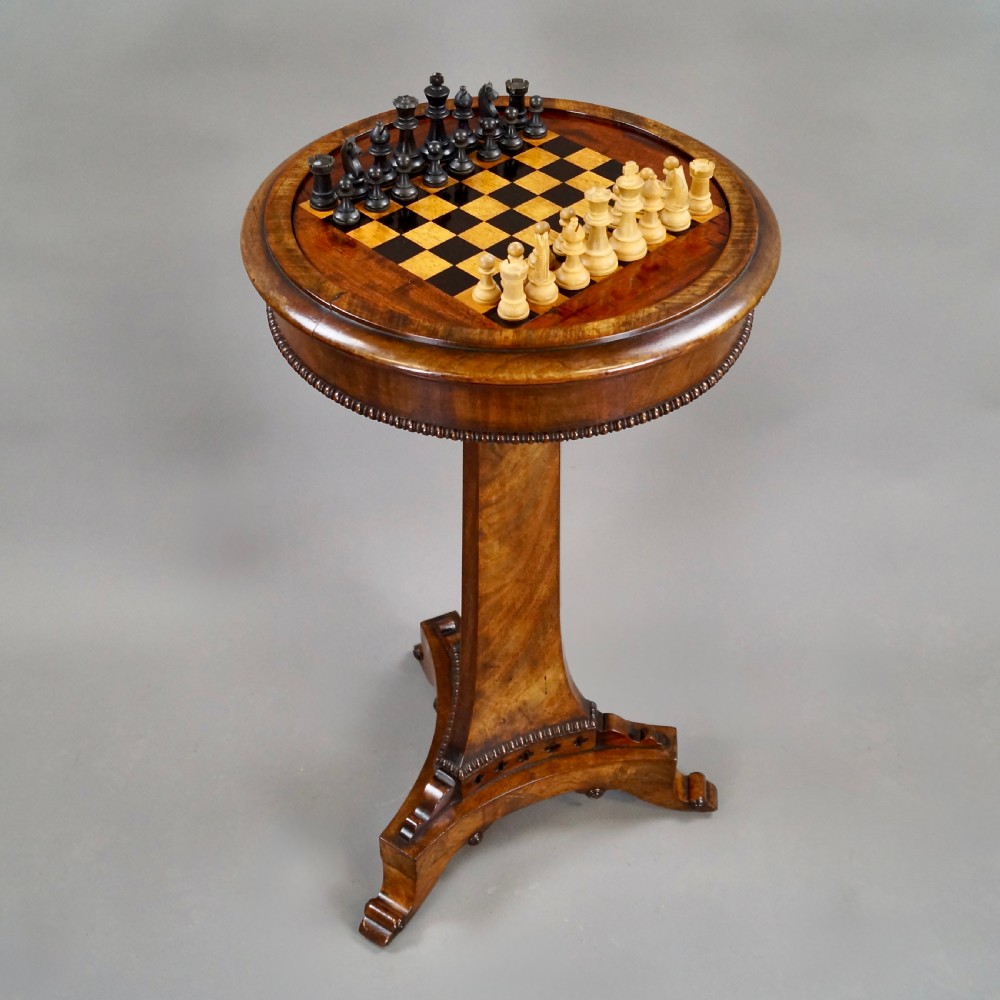 A William IV mahogany circular chess table with an inlaid board, tapered central stem, and triform base on scroll feet. View IV