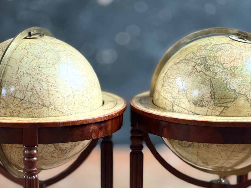 A pair of floor-standing antique globes on turned mahogany reeded legs with brass meridian rings and integral compasses set into the lower stretchers. View II