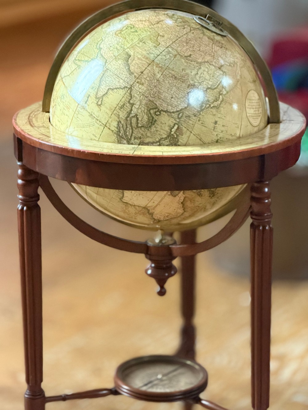 A pair of floor-standing antique globes on turned mahogany reeded legs with brass meridian rings and integral compasses set into the lower stretchers. View III