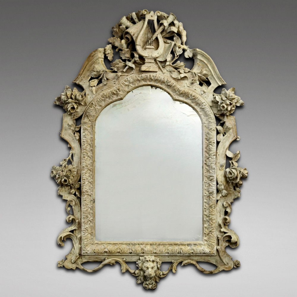 An eighteenth-century carved Italian wall mirror with a lyre crest motif, floral details, distressed off-white finish, and a lion mask base.