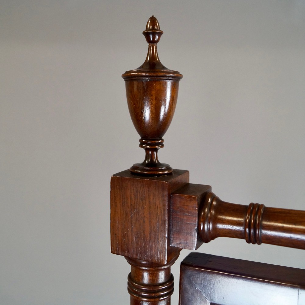 A George III mahogany cheval mirror featuring an adjustable rectangular glass plate suspended between turned vertical supports topped with urn finials and resting on splayed legs with brass castors. View II