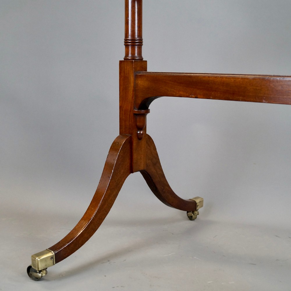 A George III mahogany cheval mirror featuring an adjustable rectangular glass plate suspended between turned vertical supports topped with urn finials and resting on splayed legs with brass castors. View IV