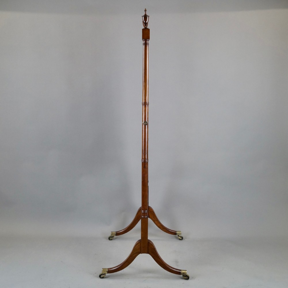 A George III mahogany cheval mirror featuring an adjustable rectangular glass plate suspended between turned vertical supports topped with urn finials and resting on splayed legs with brass castors. View V
