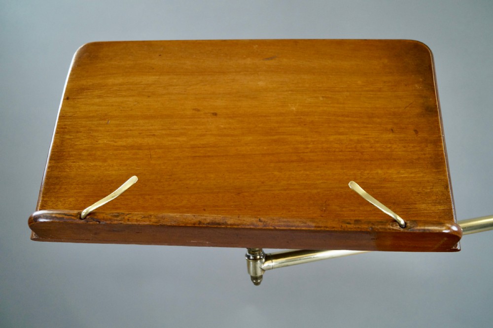 A late 19th-century Victorian reading stand with an adjustable brass stem, articulated arm holding a tilted mahogany book rest, a small central round mahogany shelf, and an ornate cast base. View IV