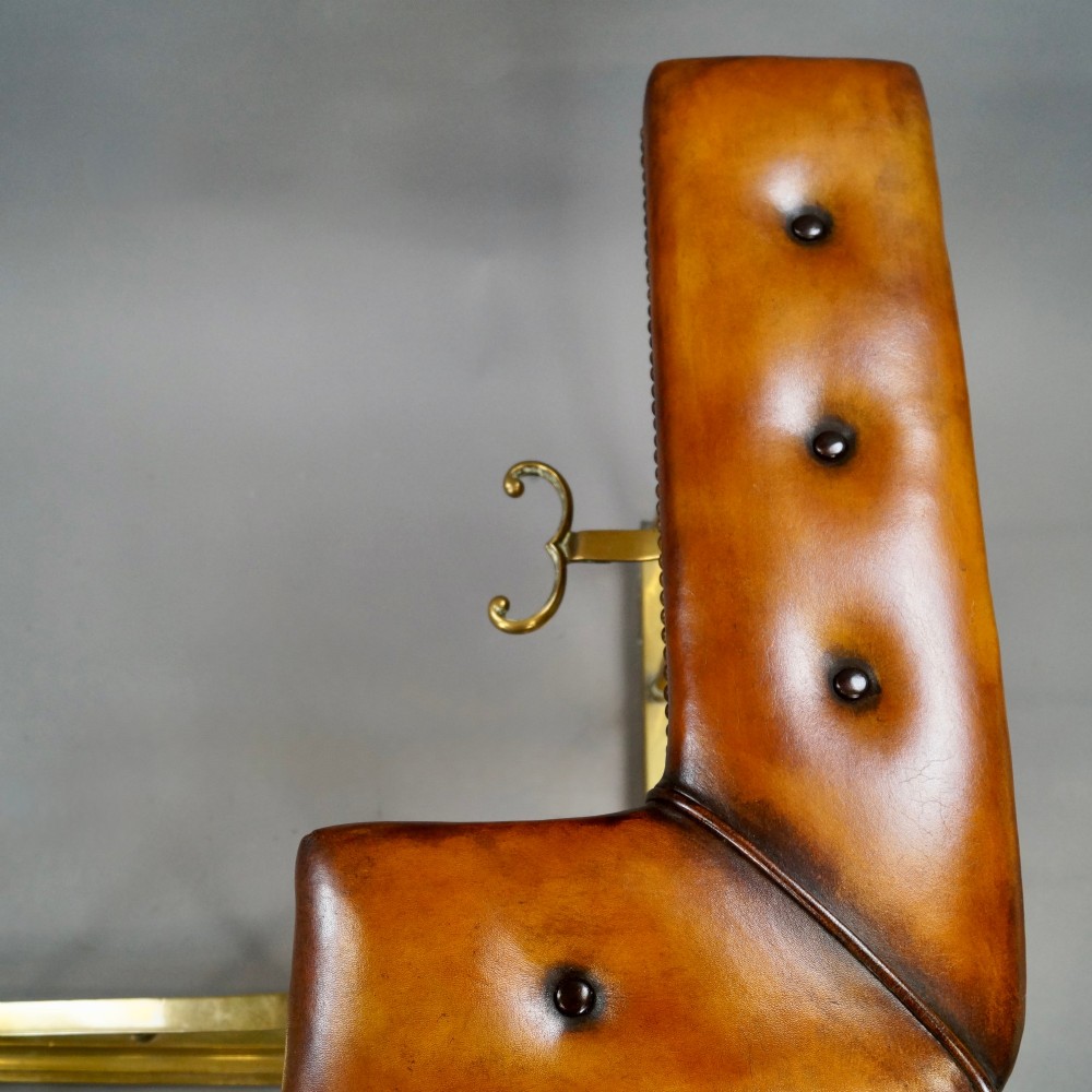 A nineteenth-century brass club fender featuring a central dipped rail, vertical brass spindles, and button-tufted tan leather corner seats. View III