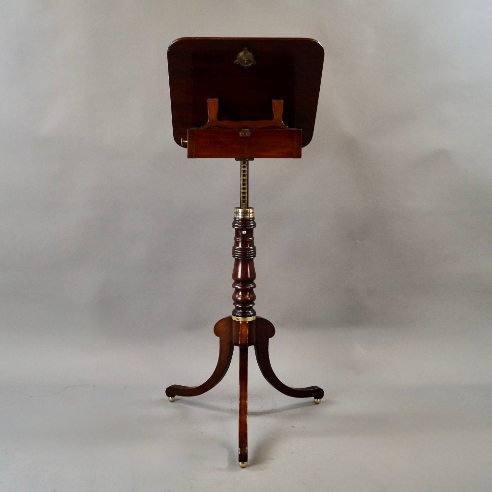 An antique Regency mahogany reading stand featuring an adjustable tilting book rest, turned central stem, brass accents, and sweeping tripod legs. View III