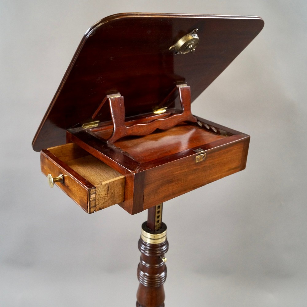 An antique Regency mahogany reading stand featuring an adjustable tilting book rest, turned central stem, brass accents, and sweeping tripod legs. View IV