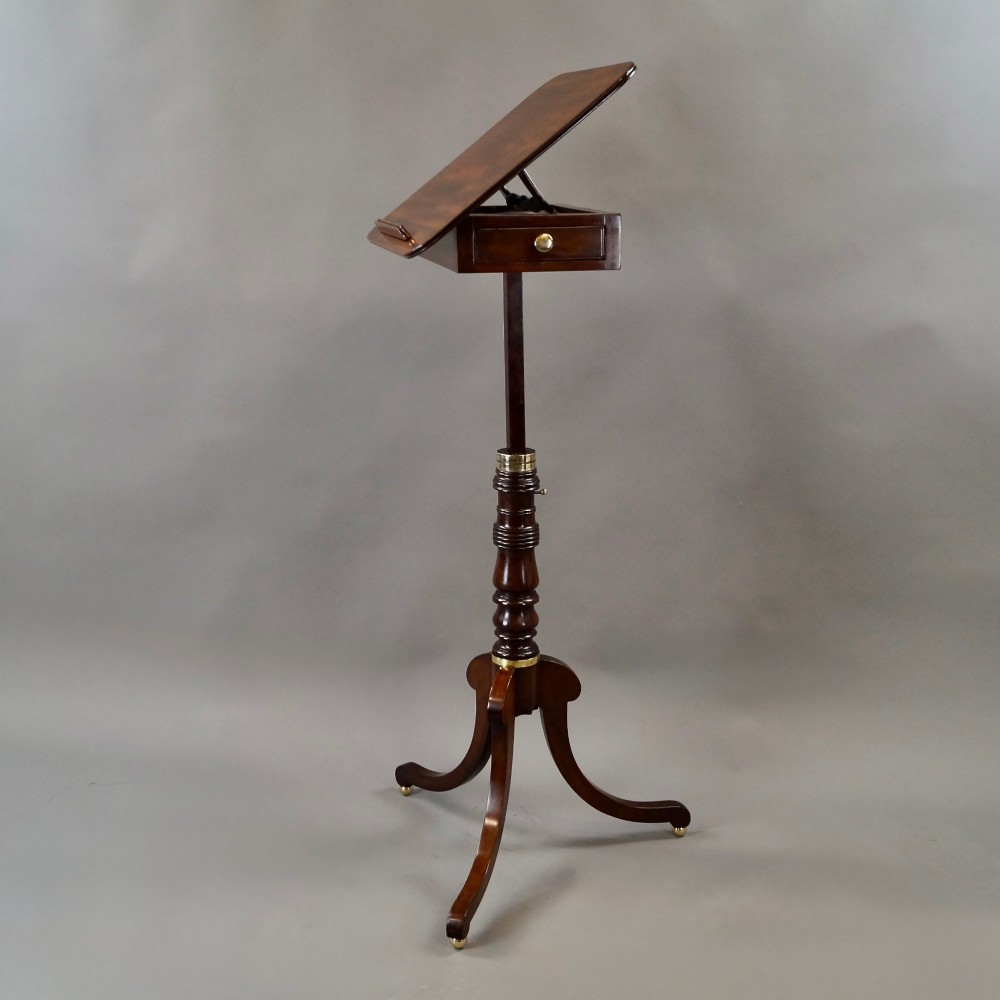 An antique Regency mahogany reading stand featuring an adjustable tilting book rest, turned central stem, brass accents, and sweeping tripod legs. View VI