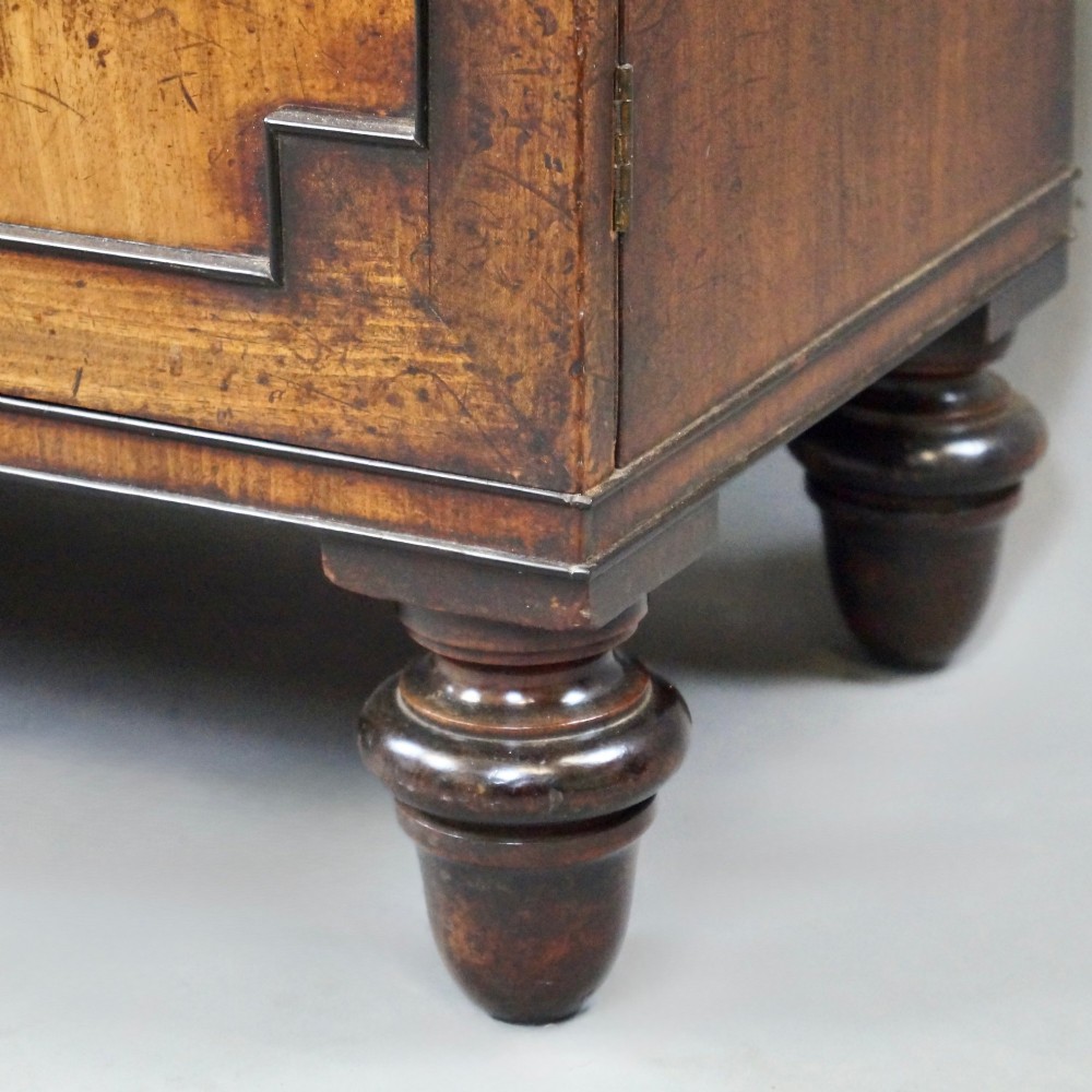 An antique Regency mahogany waterfall bookcase featuring open graduated shelves above a two-door lower cupboard resting on turned legs. View IV
