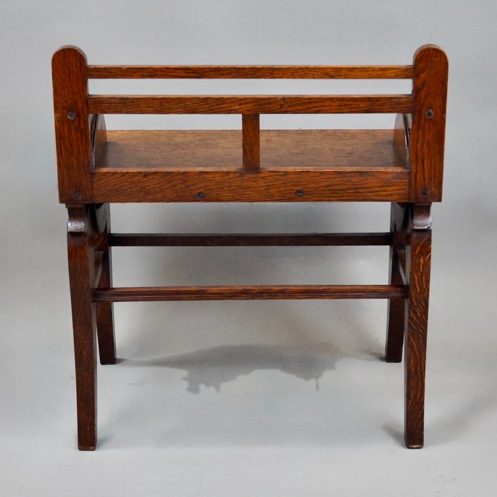 An antique solid oak hall bench featuring curved armrests with circular side panels and decorative brass shell mounts. View V