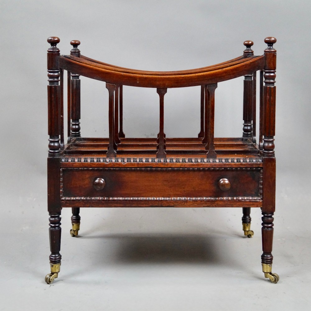 A William IV mahogany canterbury featuring four concave compartments with turned spindles, a single base drawer with wooden knobs, and turned legs on brass castors. View II
