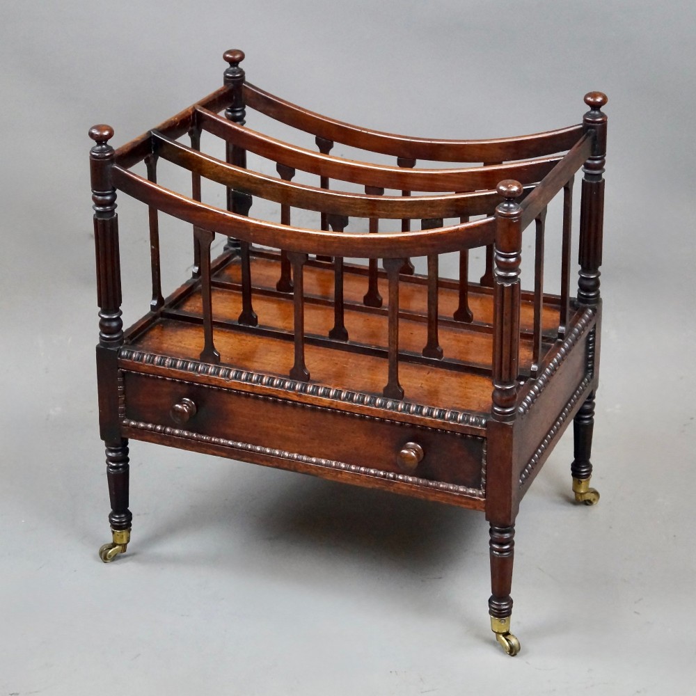 A William IV mahogany canterbury featuring four concave compartments with turned spindles, a single base drawer with wooden knobs, and turned legs on brass castors. View III