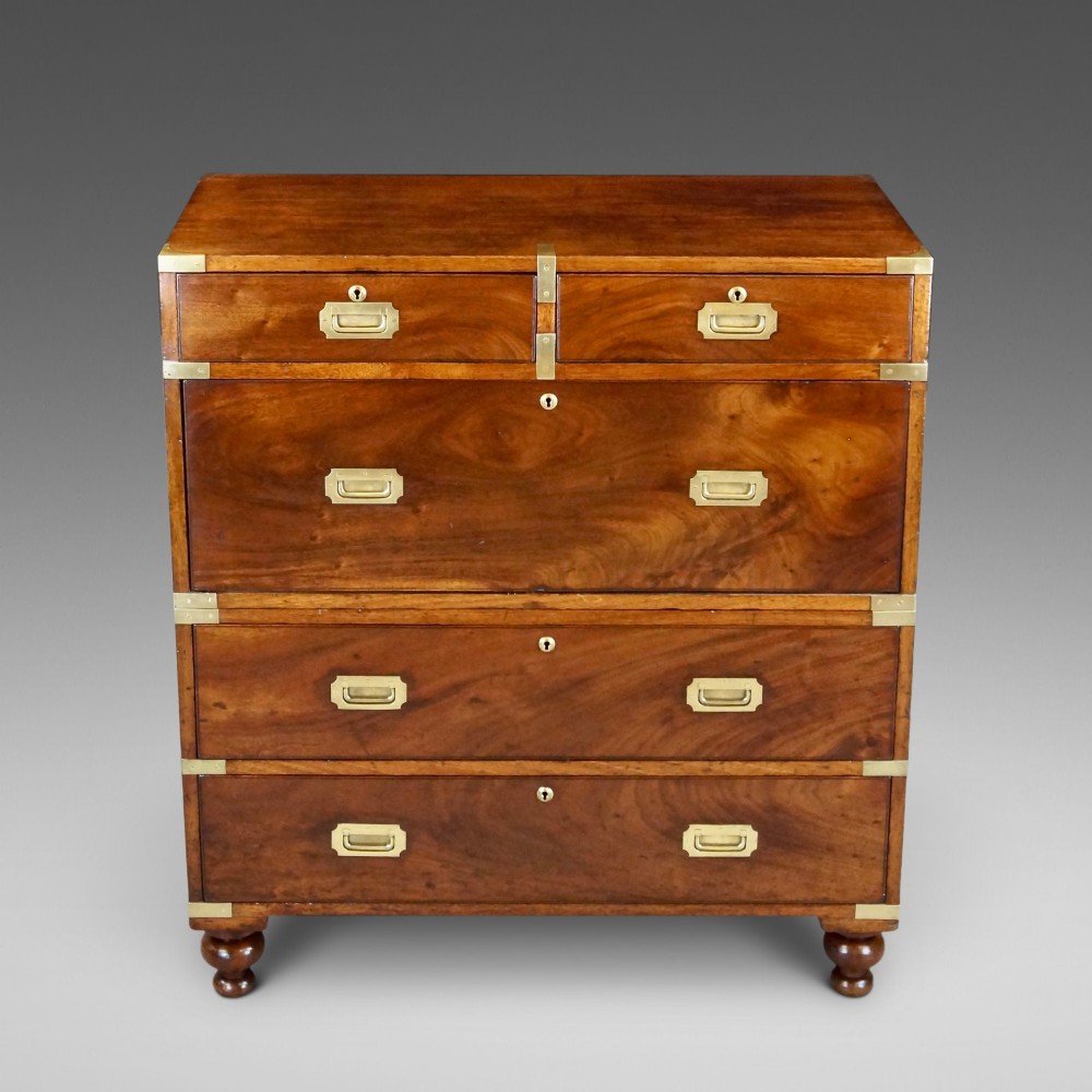 A nineteenth-century mahogany campaign chest of drawers featuring brass corner straps, flush recessed handles, and turned feet.