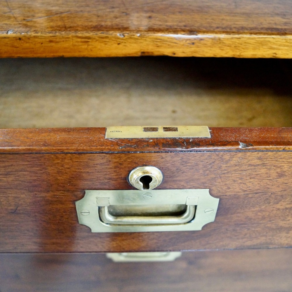 A nineteenth-century mahogany campaign chest of drawers featuring brass corner straps, flush recessed handles, and turned feet. View V