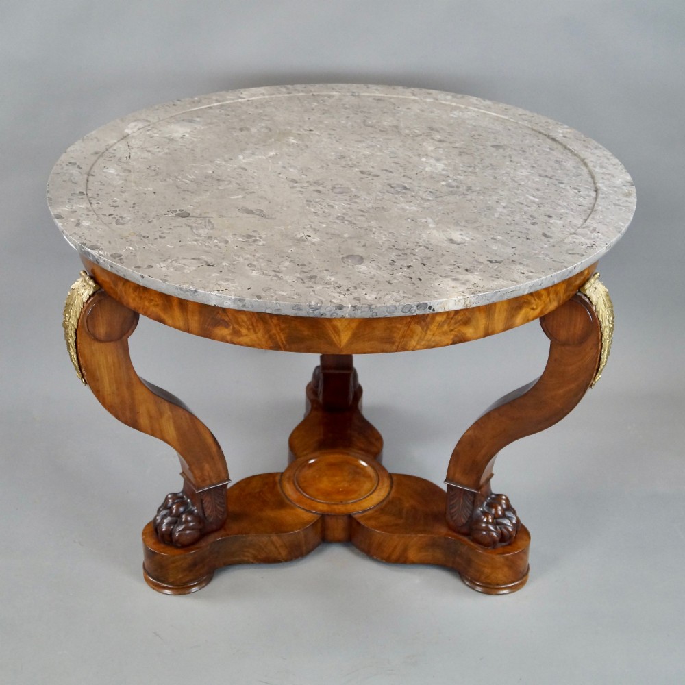 A circular French Empire mahogany gueridon table featuring a grey marble top, gilt bronze mounts, curved tripod legs, and carved lion paw feet on a plinth base. View II