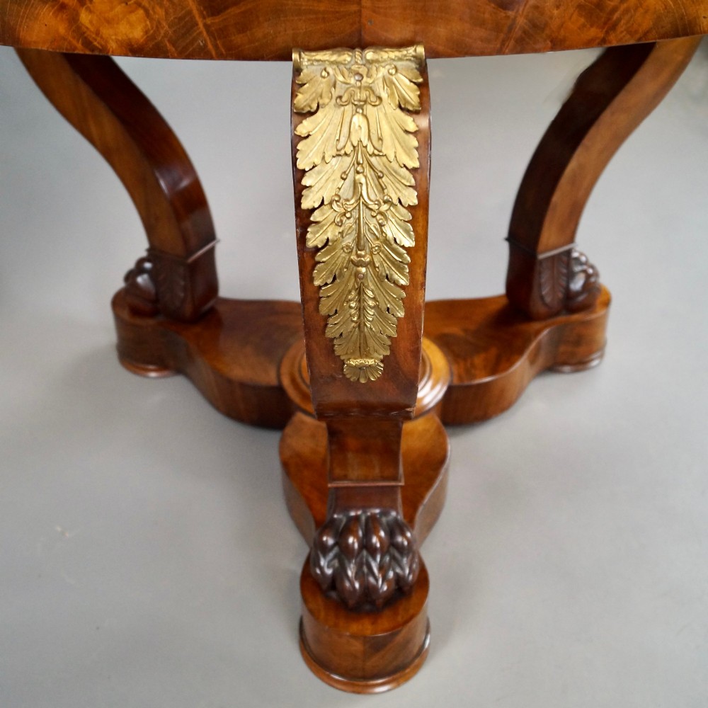 A circular French Empire mahogany gueridon table featuring a grey marble top, gilt bronze mounts, curved tripod legs, and carved lion paw feet on a plinth base. View III