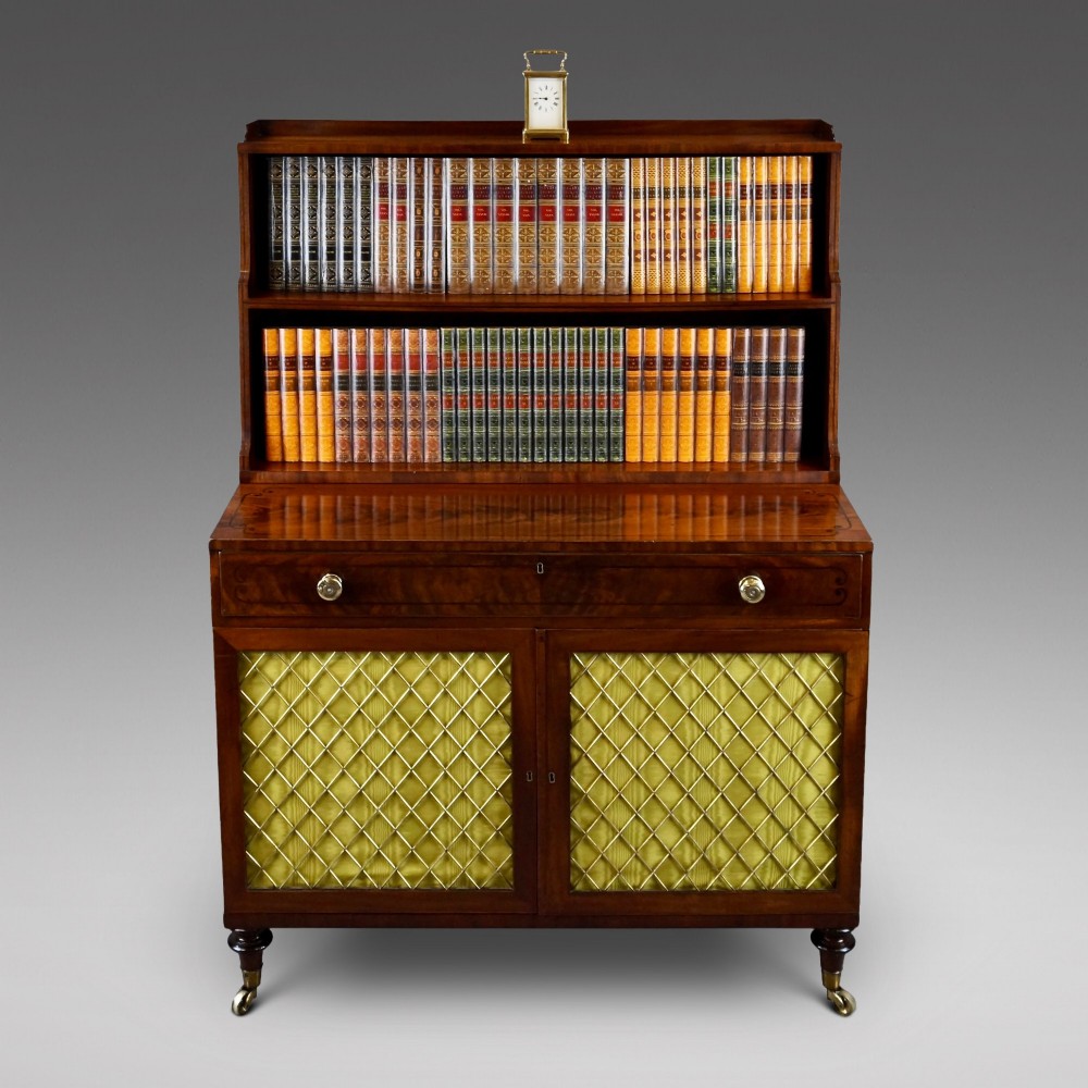 A Regency mahogany waterfall bookcase featuring graduated open shelves above a single drawer and lower cupboard doors with brass wire grilles.