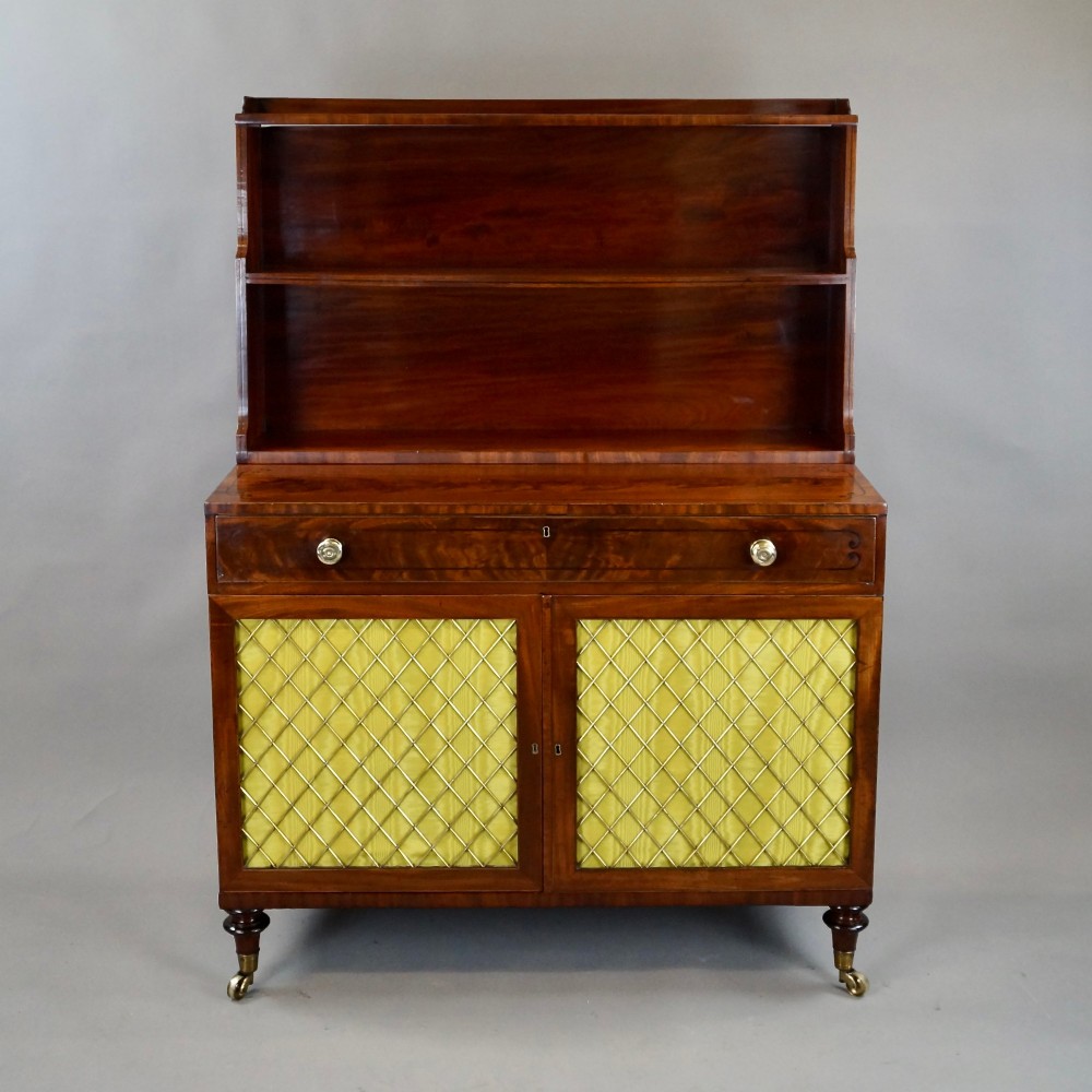 A Regency mahogany waterfall bookcase featuring graduated open shelves above a single drawer and lower cupboard doors with brass wire grilles. View II