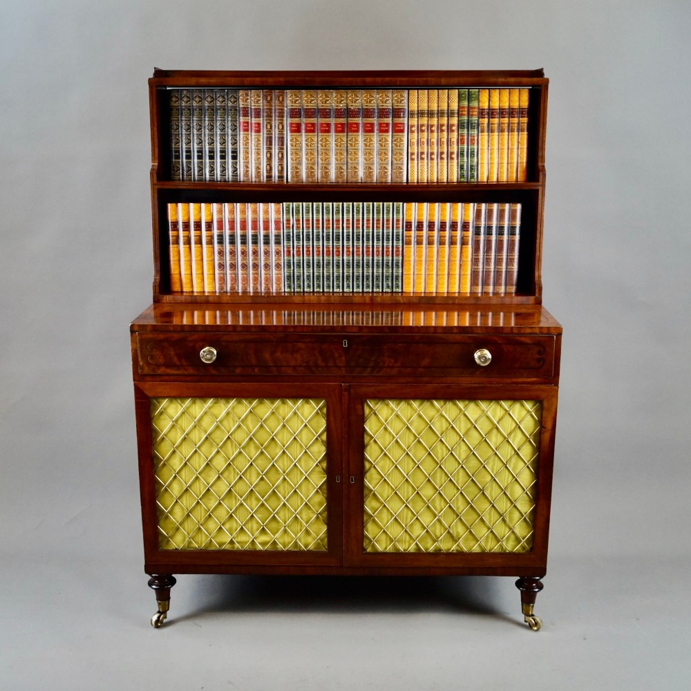 A Regency mahogany waterfall bookcase featuring graduated open shelves above a single drawer and lower cupboard doors with brass wire grilles. View V