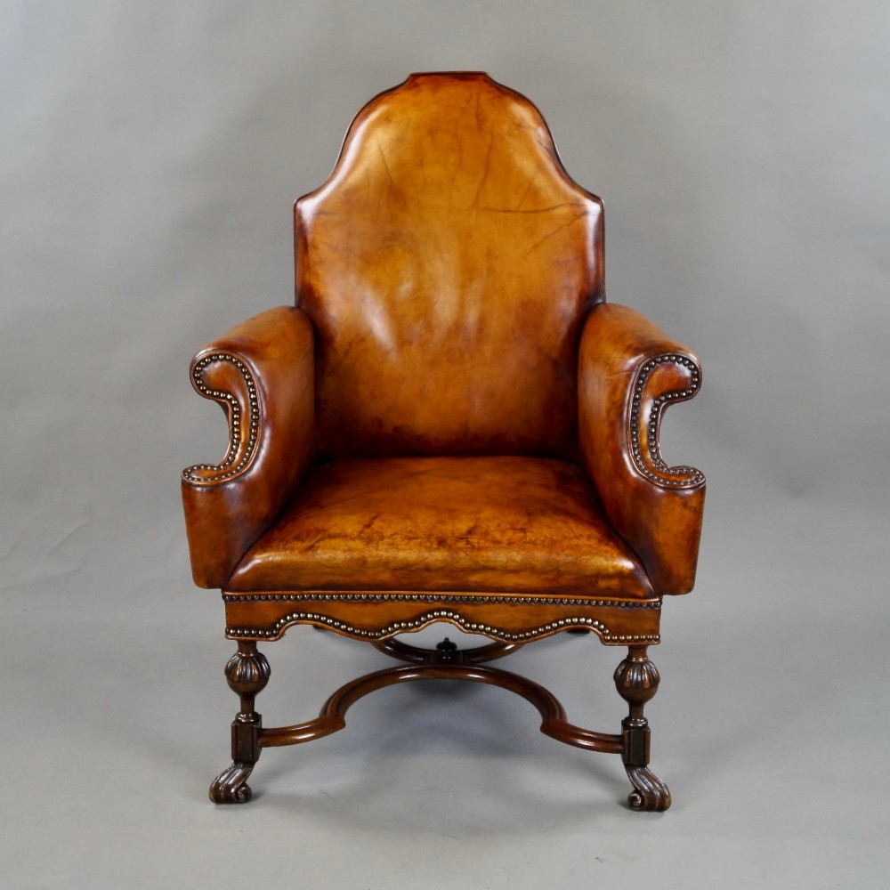 An 18th-century style tan leather armchair with brass stud trimming, scrolled arms, a shaped backrest, and carved walnut legs with a curved stretcher. View III