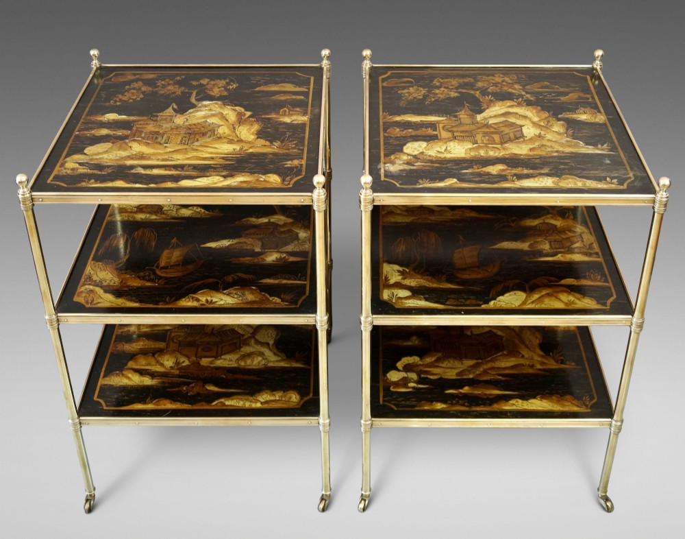 A pair of three-tiered brass etagere side tables featuring black lacquered shelves decorated with gold chinoiserie landscape scenes. View II