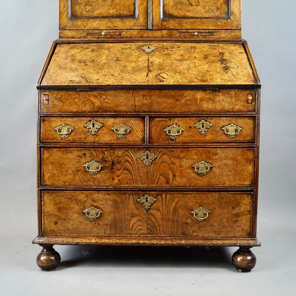 A William and Mary burr elm bureau bookcase featuring a twin-panel upper cabinet over a slant-front desk and four lower drawers on turned bun feet. View II
