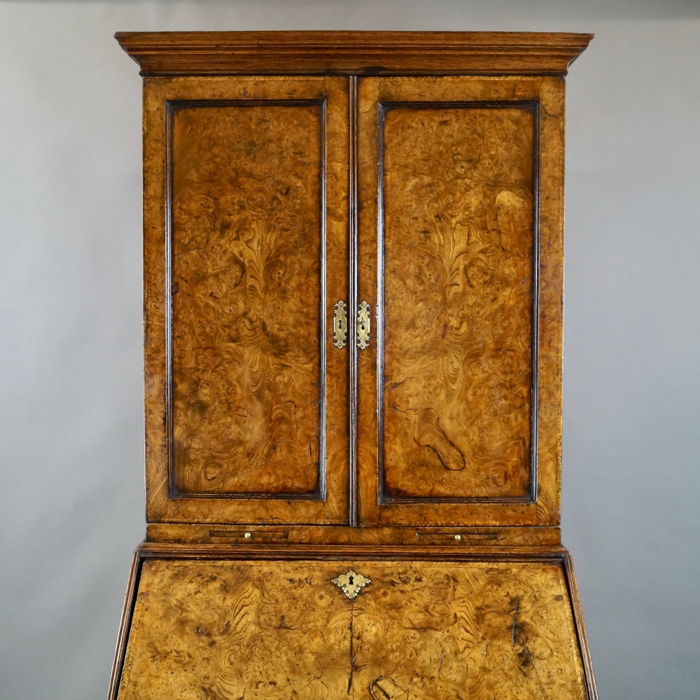 A William and Mary burr elm bureau bookcase featuring a twin-panel upper cabinet over a slant-front desk and four lower drawers on turned bun feet. View III