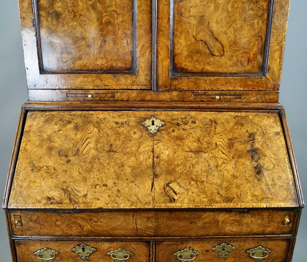 A William and Mary burr elm bureau bookcase featuring a twin-panel upper cabinet over a slant-front desk and four lower drawers on turned bun feet. View V