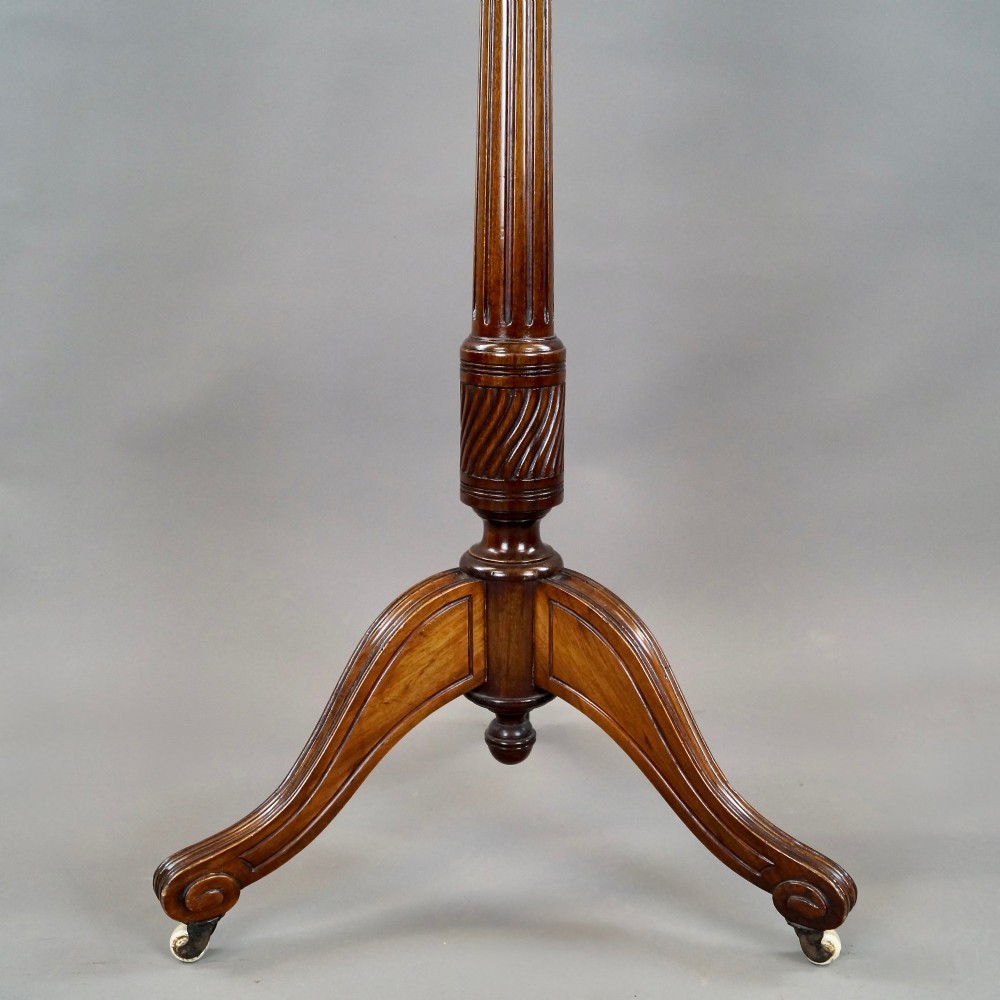 An antique mahogany duet music stand featuring a double-sided fretted lattice rest, brass adjustment mechanism, turned stem, and tripod base with castors. View VI
