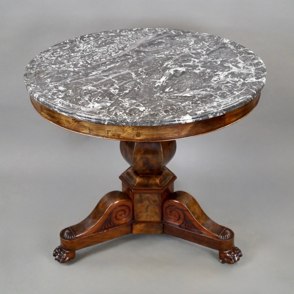 A 19th-century French circular gueridon centre table featuring a flame mahogany veneer pedestal base and a grey veined marble top resting on a triform plinth. View II